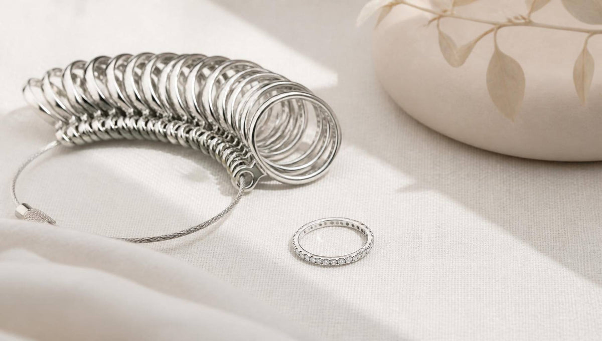 A set of polished ring sizers beside a slim diamond eternity ring on pale ivory linen