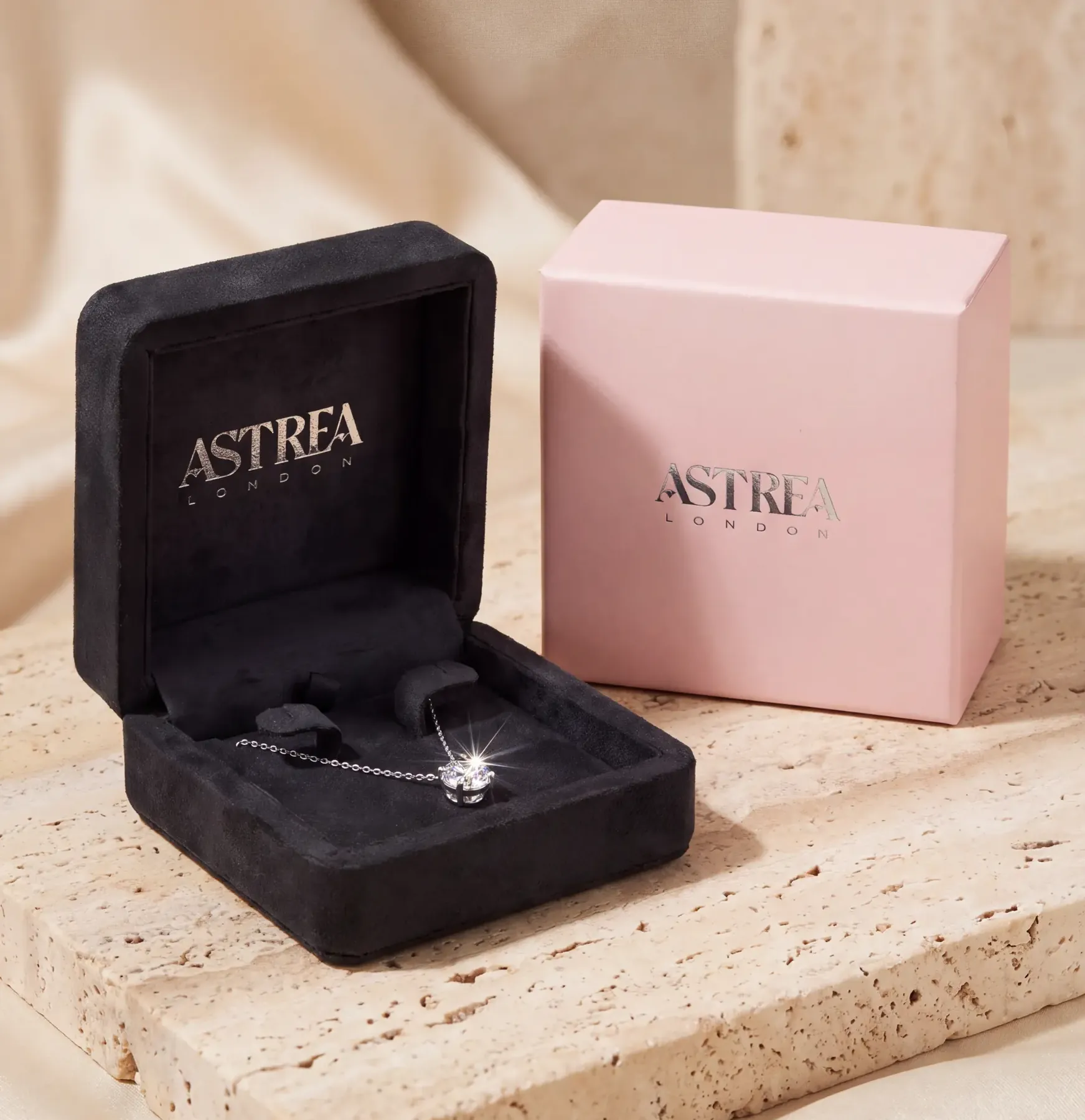 Astrea London pendant packaging — grey suede case and pink outer box